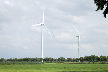 Landscape photo of three wind turbines in meadow farming field. Green renewable energy, global...