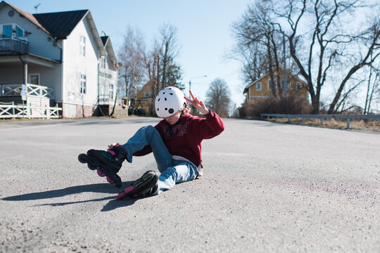 girl doing the peace sign whilst roller blading outside in the street