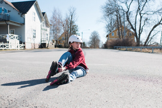 girl getting ready to roller blade in the street at home
