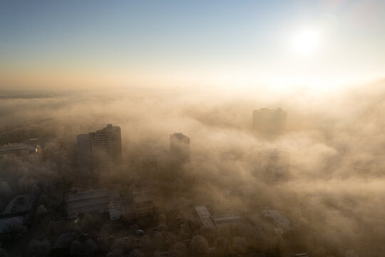 Aerial picture of high-rise buildings in the morning fog during dramatic sunrise