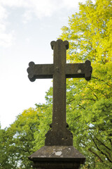 Stone big cross cemetery graveyard with garden park trees. Ceremony religios statue faith concept.