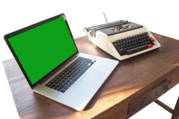 A modern laptop paired with a vintage typewriter on a wooden desk, symbolizing the evolution of writing tools.
