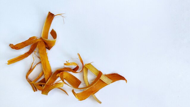 Close up of dry bark chips on a white surface, this is sappanwood, which is commonly used for herbal medicine.