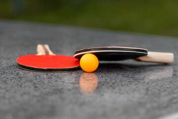 Table tennis, a yellow ball and rackets are lying on the table, outdoor sport leisure activity,...