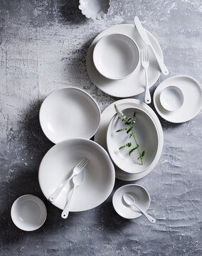 Top view of various white ceramic dishes on textured background