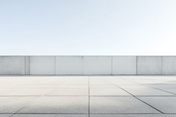 Obraz premium Empty rooftop paved with light gray concrete, a low wall running horizontally along the top edge, against a pale blue sky