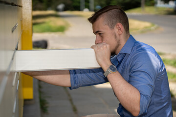 A Young Man Engaging with a ModernMailbox in a Vibrant Urban Environment and Setting
