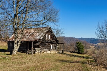 Obraz premium Rustic log cabin in scenic rural landscape