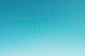 A soft, blurred sky gradient transitions from a pale blue to a vibrant turquoise