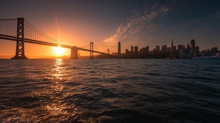 Fototapeta premium A wide sunset view across Bay, with the bridge illuminated and downtown rising in soft golden hues..