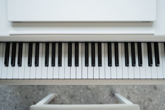 White digital piano with stool on stone floor