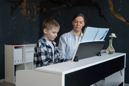 Young boy learning to play piano with guidance