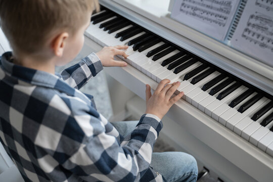 Child learning to play the piano with music sheets