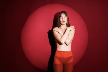 Young woman posing against a red circular backdrop in studio