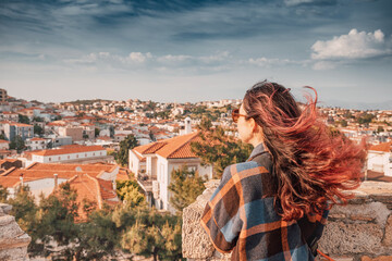 Young woman admiring traditional white houses with terracotta roofs in Alacati, a popular travel...