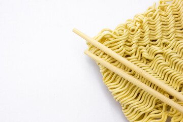 Dried raw instant noodles with a chopstick on a white background, copy space, background and texture.