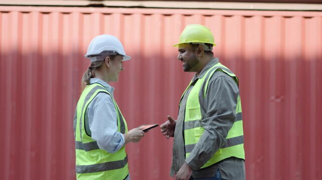 Happy dealing shaking hands two foreman worker working checking at container cargo harbor to loading containers, engineer man having hand shack with his woman boss after work discussion