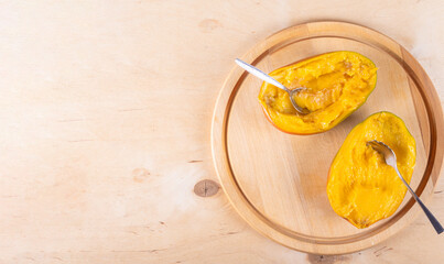 Top view of two halves of mango and spoons on wooden background