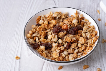 Healthy granola bowl with nuts and raisins served on a wooden table during breakfast time