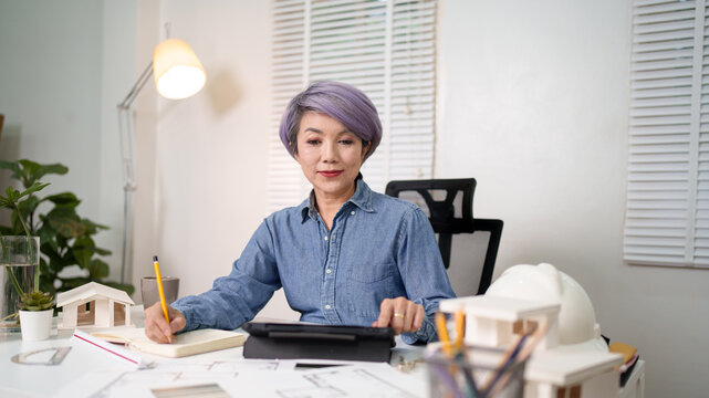 Asian Woman Architect at Work Analyzing Blueprints for Building Design Plans and Inspecting Home Construction Asian Woman Focused on Project