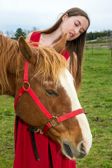 A young woman in a red dress with a horse