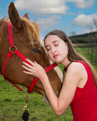 A young woman in a red dress with a horse