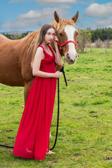 A young woman in a red dress with a horse