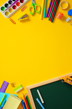 Flat lay composition with school supplies : chalkboard, pencils, and notebooks on yellow desk