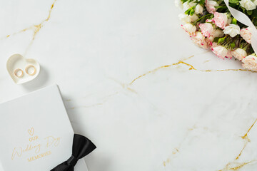 Wedding flat lay. Rings, rose bouquet, and album on marble background.
