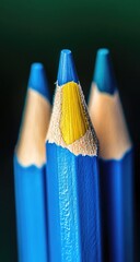 Close-up of three sharpened blue pencils, one with a sliver of yellow exposed