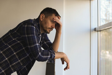 Obraz premium Depressed man near window in building. Mental health problem