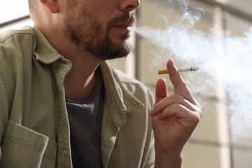Man smoking cigarette on blurred background, closeup