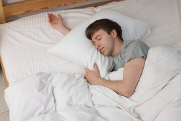 Young man sleeping in bed at home, above view