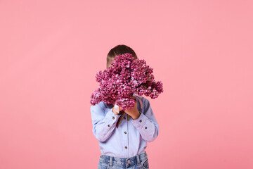 Little boy with bouquet of lilac flowers on pink background