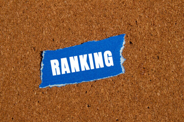 Ranking message written on ripped torn blue paper piece on brown background. Conceptual ranking...