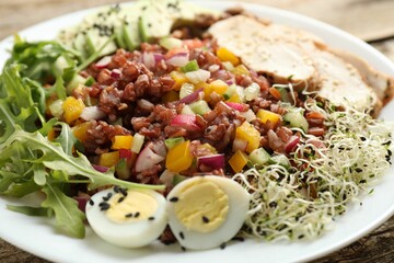 Tasty salad with brown rice on wooden table, closeup