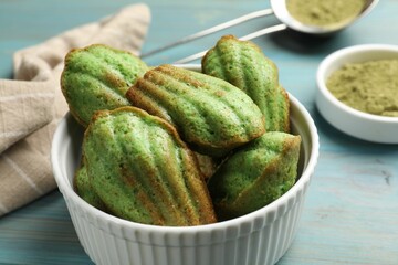 Tasty matcha madeleine cakes on light blue wooden table, closeup