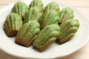 Tasty matcha madeleine cakes on light wooden table, closeup