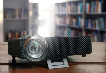 Modern video projector on wooden table in library