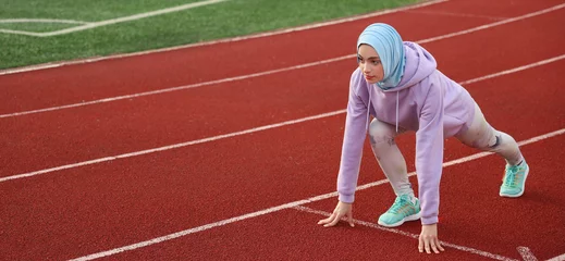 Fotobehang Sporty Muslim woman getting ready to run at stadium © Pixel-Shot