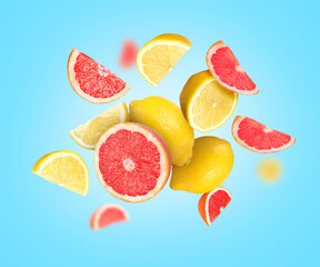 Different fresh citrus fruits in air on light blue background