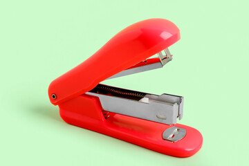 Red stapler on green background
