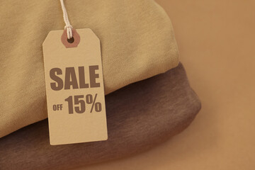 Sale tag and clothes on pale brown background, closeup