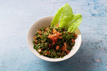 Fresh Lebanese tabbouleh salad with parsley, tomatoes, and lettuce leaves.
