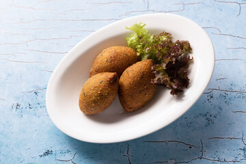 Crispy Lebanese kibbeh served on white plate with fresh lettuce.