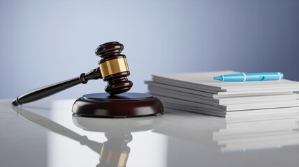 A professional legal still life photograph featuring a black wooden judge's gavel with a gold band against a reflective gray surface