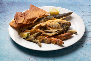 Assorted fried fish and crispy bread served with lemon wedges.