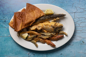 Assorted fried fish and crispy bread served with lemon wedges.