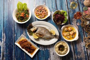 Lebanese seafood and mezza spread styled over rustic blue table.