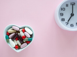Top view, flat lay a light blue, a heart-shaped bowl filled with various pills and capsules and...